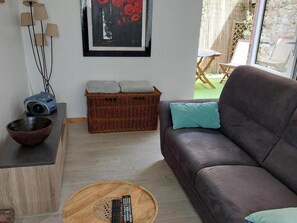 A living room with a sofa, a coffee table, a basket, a framed artwork, and a projector on a stand. - Terraced house in Barfleur with private courtyard - Pets allowed (Barfleur)