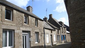 A narrow street lined with stone buildings, featuring a mix of residential and commercial properties. - Terraced house in Barfleur with private courtyard - Pets allowed (Barfleur)