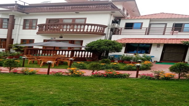 Un hotel con jardín, que incluye una mesa y sillas de madera, rodeado de plantas y flores en macetas.