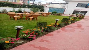 Un patio con mobiliario exterior, un camino y macizos de flores.