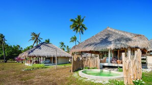 Un resort tropicale con capanne a tetto di paglia, una piscina e palme.