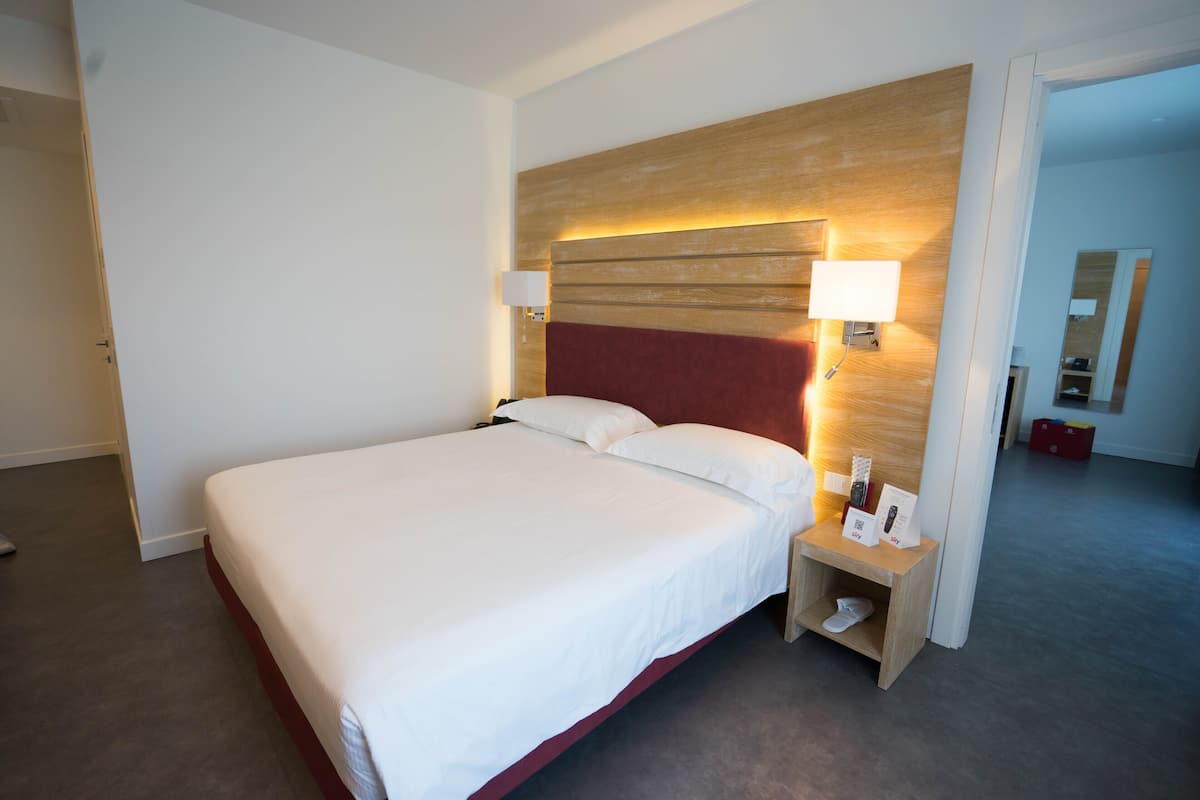 Ein Hotelzimmer mit einem großen Bett, einem Holzkopfteil, zwei Nachttischlampen und einem kleinen Regal mit einem Schuh.