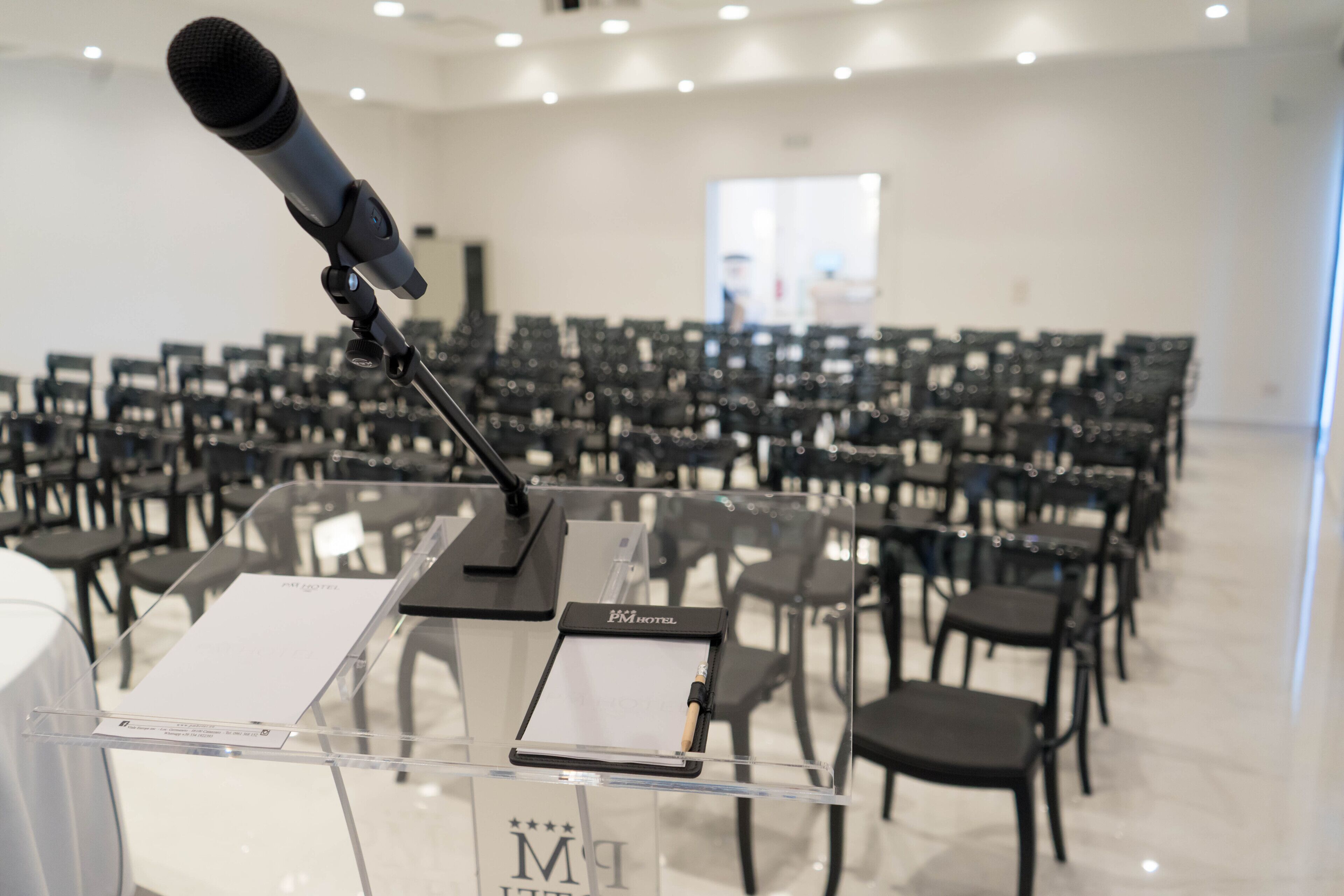 Une salle de conférence équipée d’un pupitre, de chaises et d’un microphone.