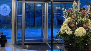 Entrada de hotel con puerta giratoria, un candelabro y un arreglo floral.
