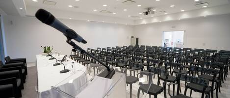 Un salón de conferencias con filas de sillas, un atril y un micrófono.