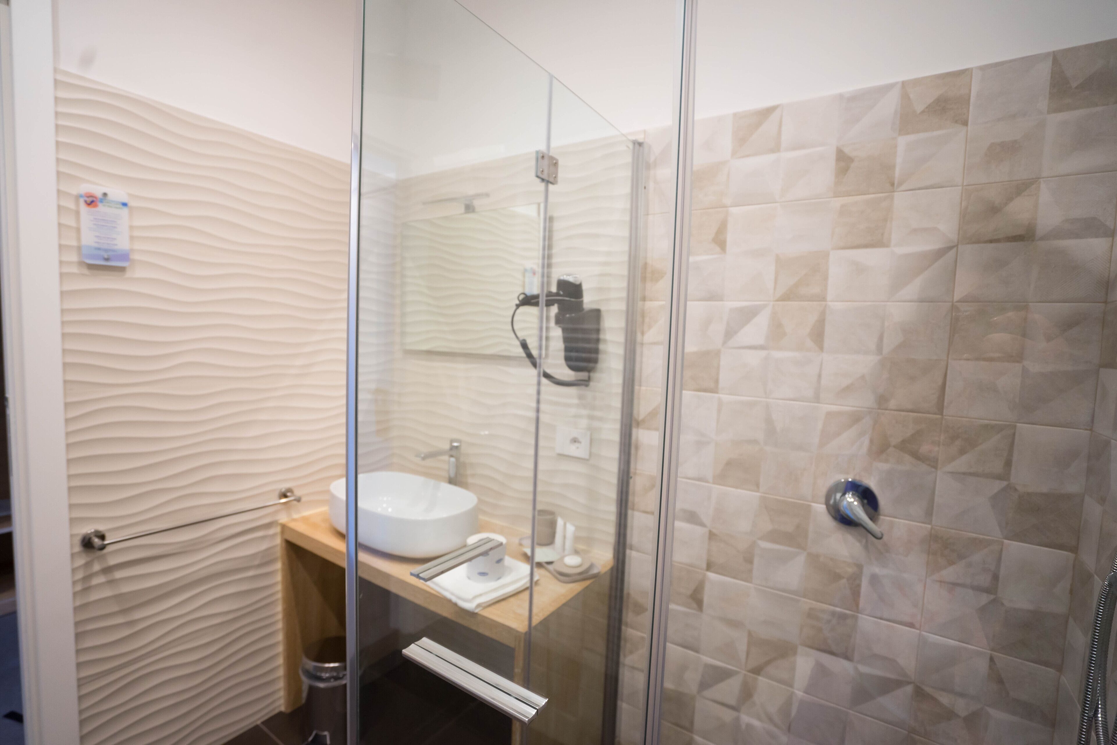 A modern bathroom with a glass shower enclosure, a sink, and a towel rack.