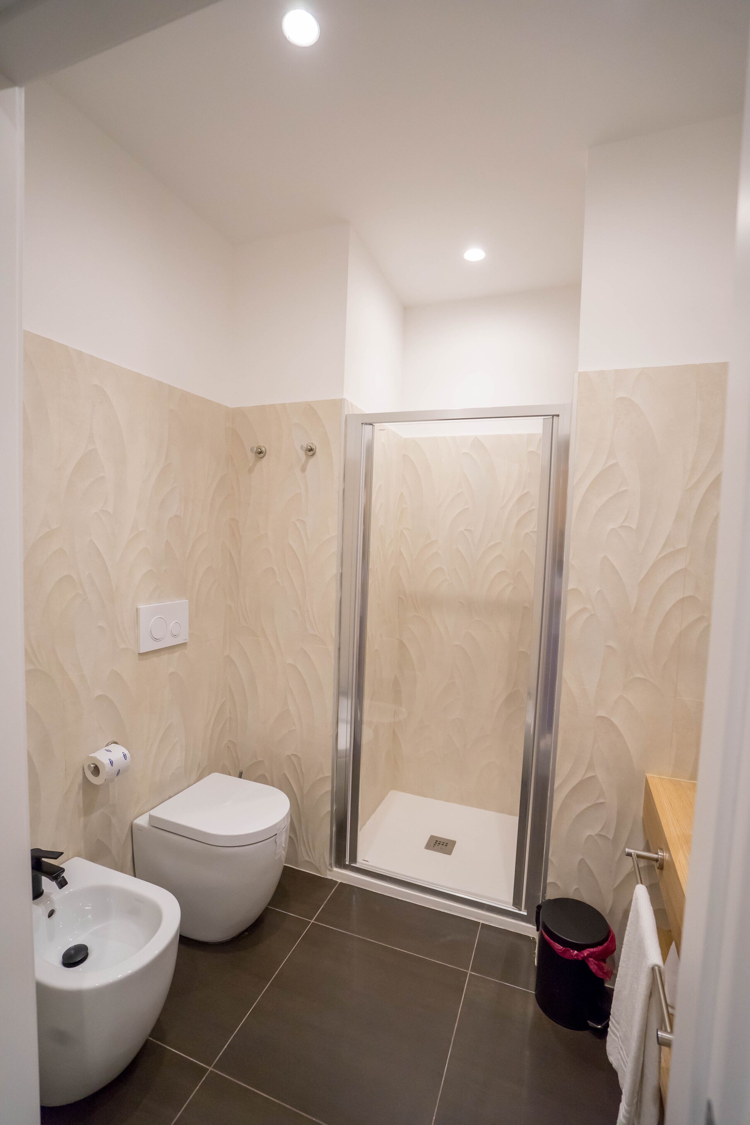 A bathroom with a shower, toilet, bidet, and sink.