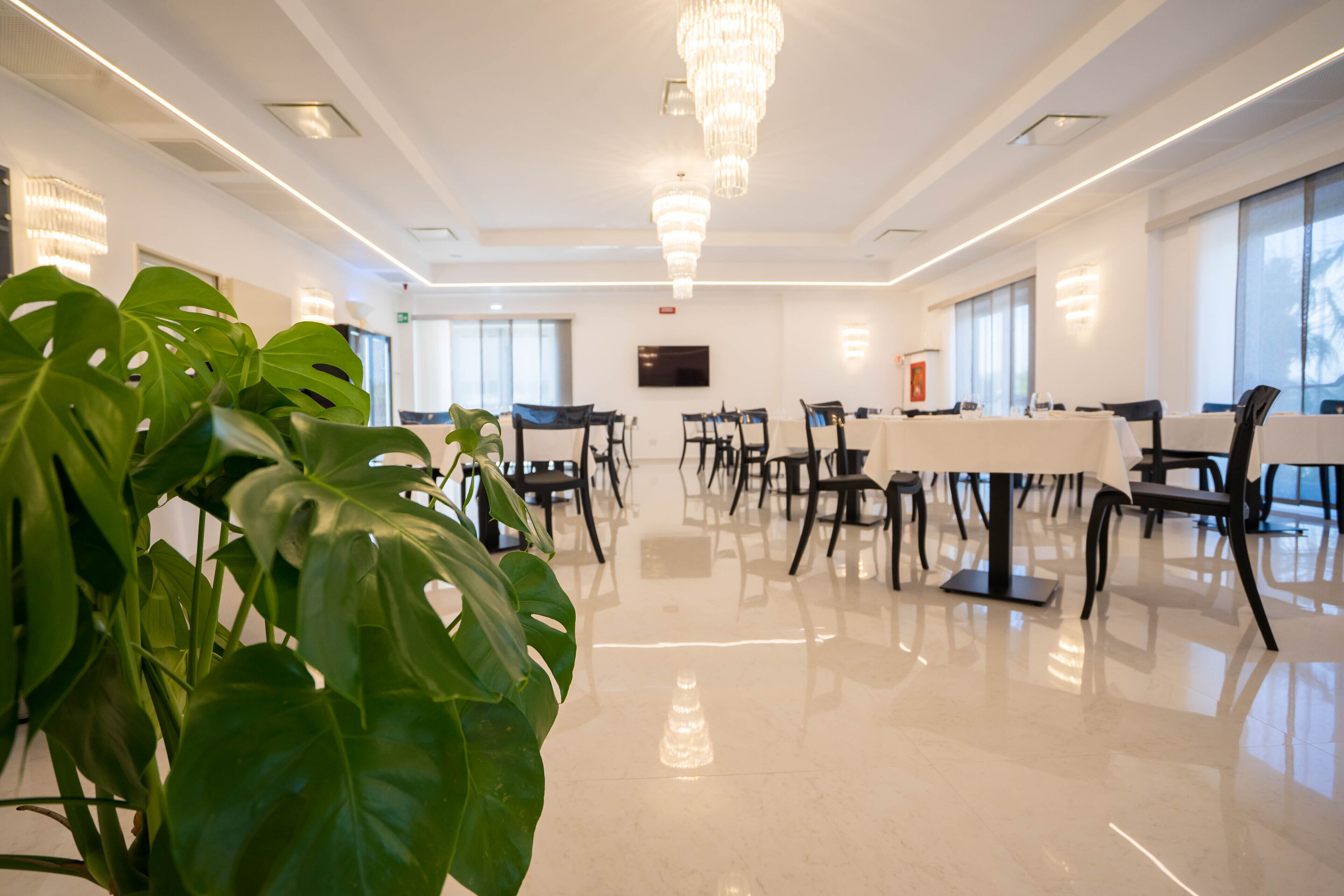 Une salle de conférence spacieuse, dotée d’un plancher ciré, de chaises modernes, d’une grande table et d’un lustre.