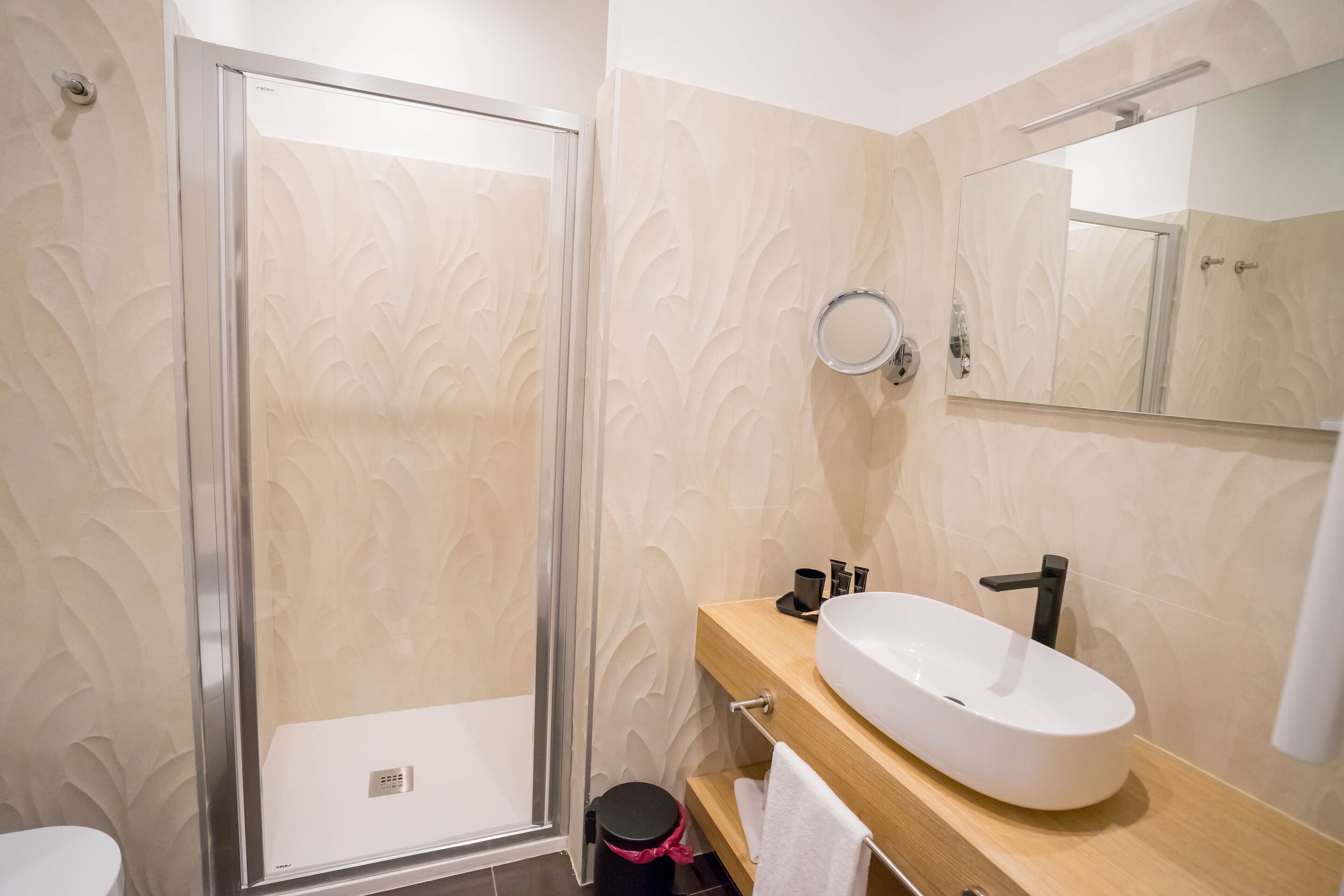 Une salle de bain avec une douche à parois de verre, un lavabo blanc et un miroir au-dessus.