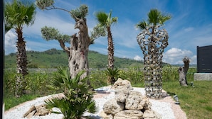 Un jardín ajardinado con palmeras, rocas y vistas a un paisaje montañoso.