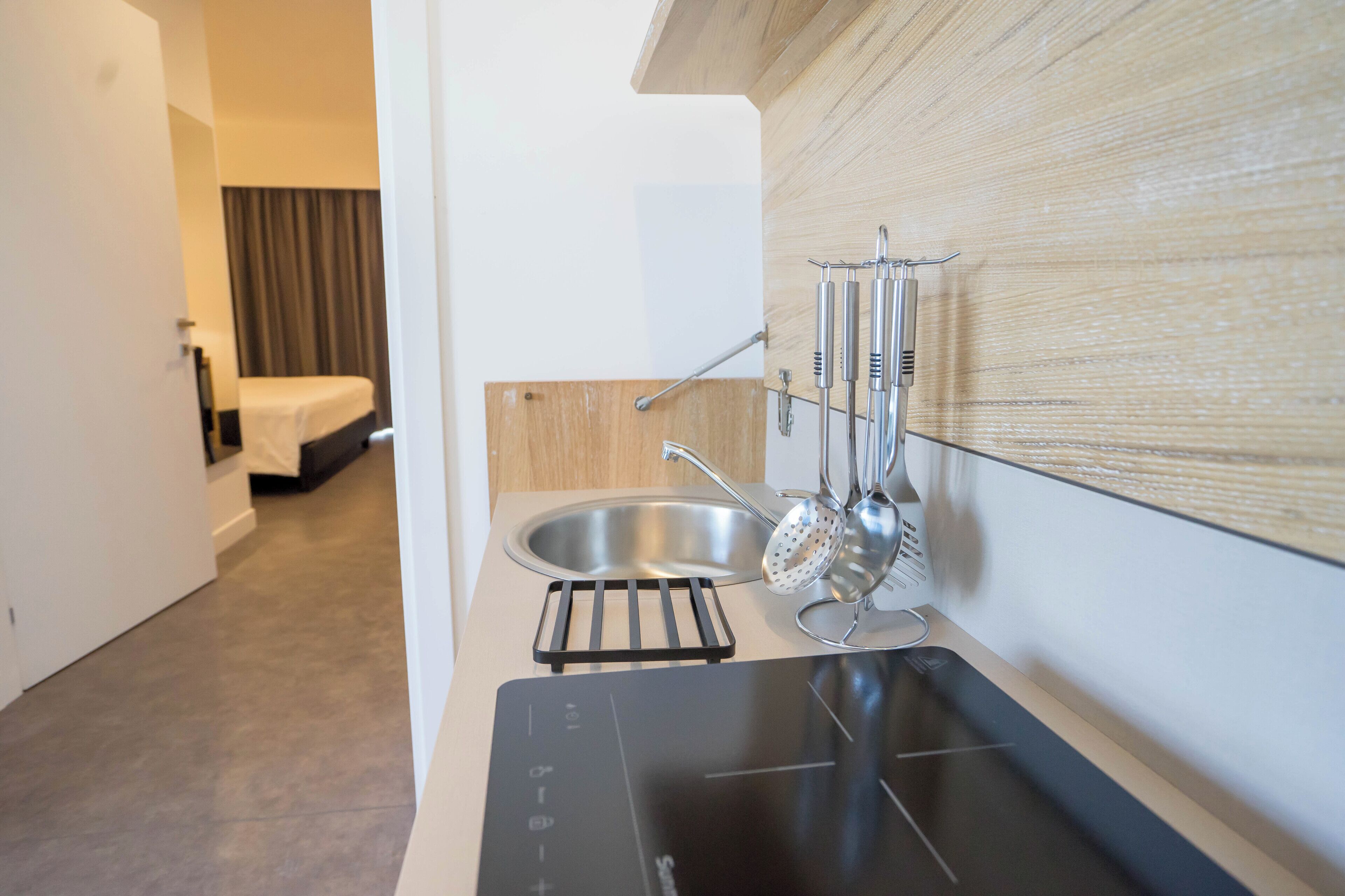 Una cocina moderna con placa de inducción integrada, un lavamanos de acero inoxidable y un escurreplatos.
