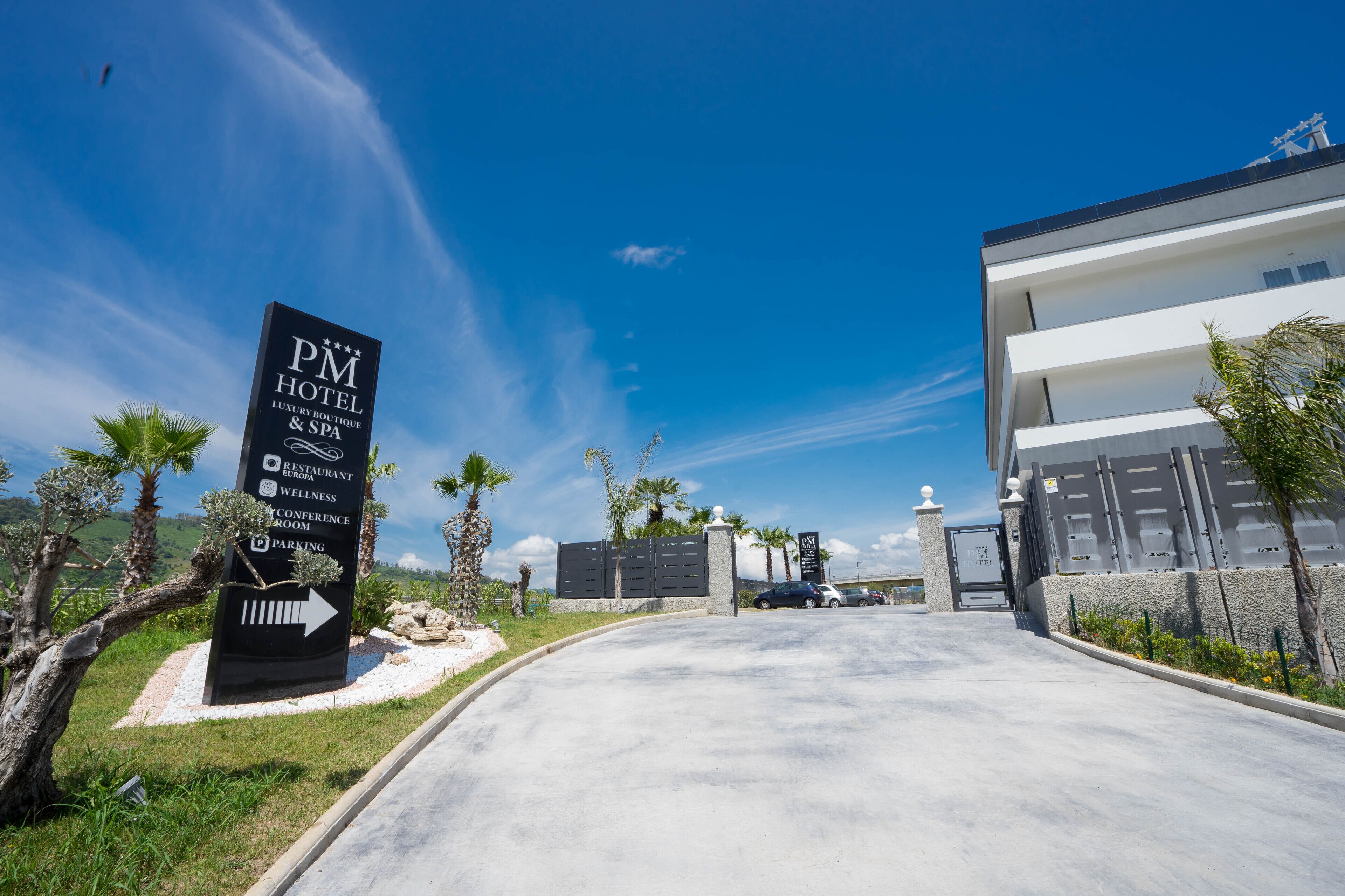 A modern hotel entrance with a sign indicating amenities like a restaurant, wellness center, and conference room.