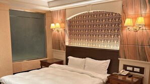 A hotel room with a large bed, two bedside tables, a nightstand, and a patterned headboard. - Duke Business Hotel (Taoyuan City)