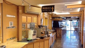 A hotel lobby with a reception desk, a coffee machine, and a sign indicating the exit. - Duke Business Hotel (Taoyuan City)