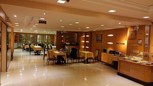 A spacious hotel dining area with multiple tables and chairs, a reception desk, and a clock on the wall. - Duke Business Hotel (Taoyuan City)