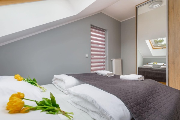 A view of a bright, attic-style bedroom with stylish furnishings and a skylight.
