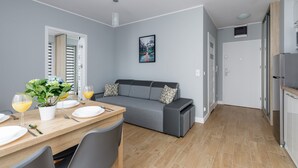 Una cucina moderna con zona pranzo, divano grigio e un quadro appeso al muro.