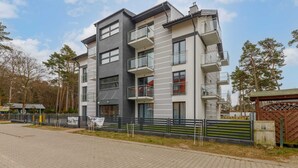 Un edificio residenziale a più piani con balconi, una strada privata con lastricato e un ingresso recintato.