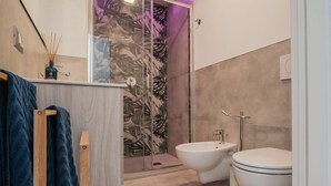 A modern bathroom with a shower, bidet, and toilet.