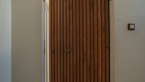 A wooden door with a handle, a small light switch on the wall, and a partially visible door frame.