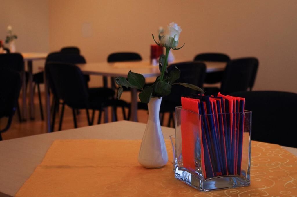 Une table à manger avec un vase blanc et un récipient en verre contenant des serviettes rouges.