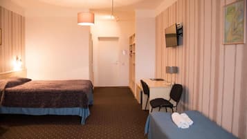Una habitación de hotel con dos camas, un escritorio, una silla y un televisor en la pared.