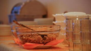 A clear glass bowl with a spoon on a table, accompanied by a glass jar and a white container.