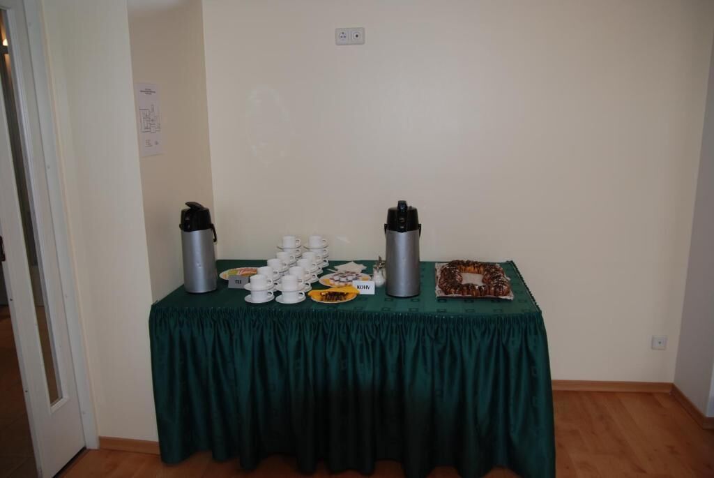 Una mesa con tazas de café, una termo y un plato de comida en una habitación con una puerta y un interruptor de luz en la pared.