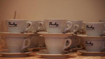 Varios tazas y platillos de cerámica blanca con el nombre de marca "Paulig" y el lema "Café Premium Desde 1874" impresos.