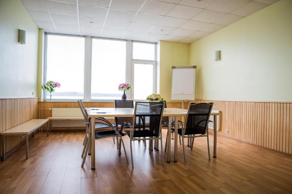 Una sala de conferencias con una mesa grande, seis sillas, dos ventanas y una pizarra.