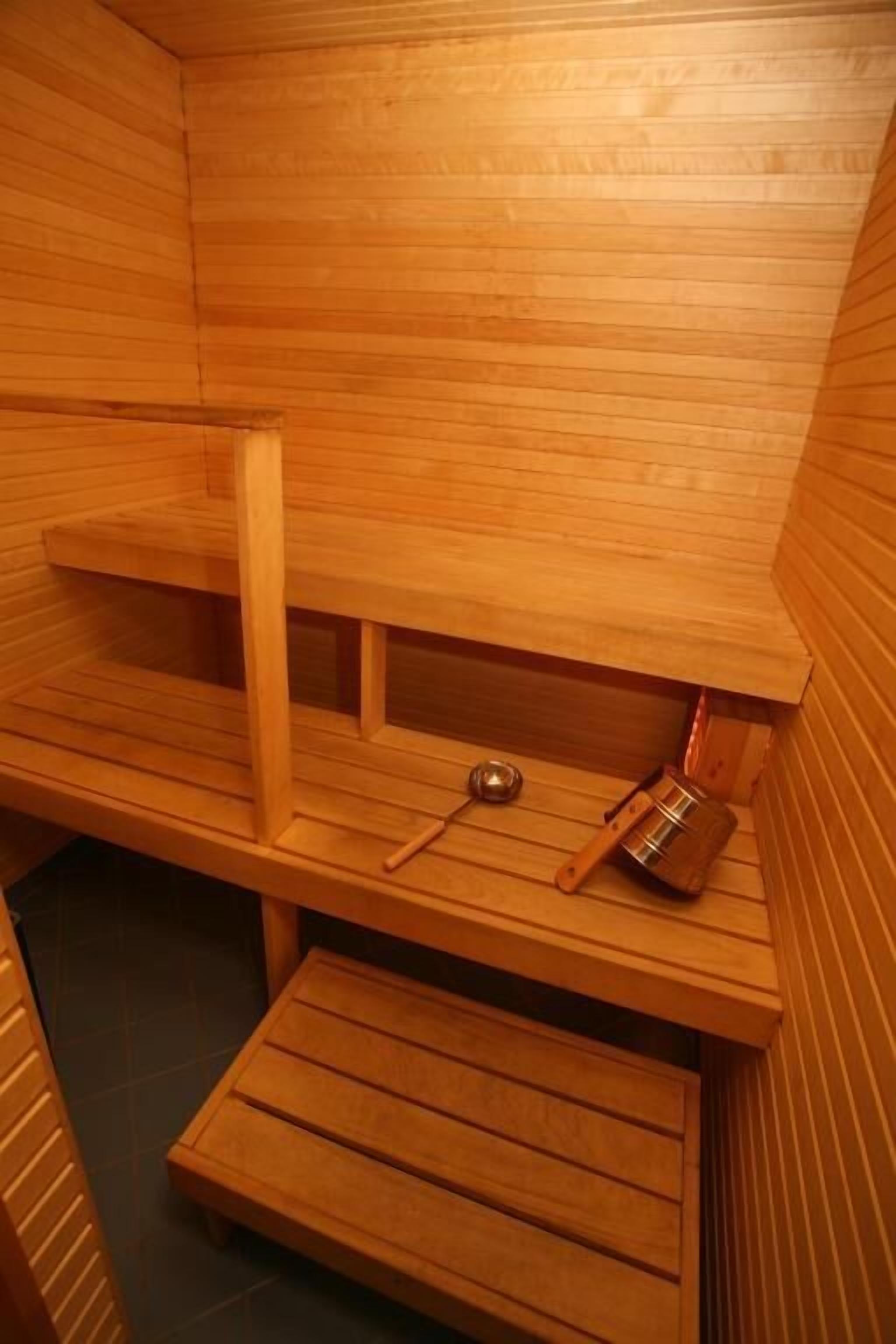 Una sauna con bancos de madera y un recipiente de metal.