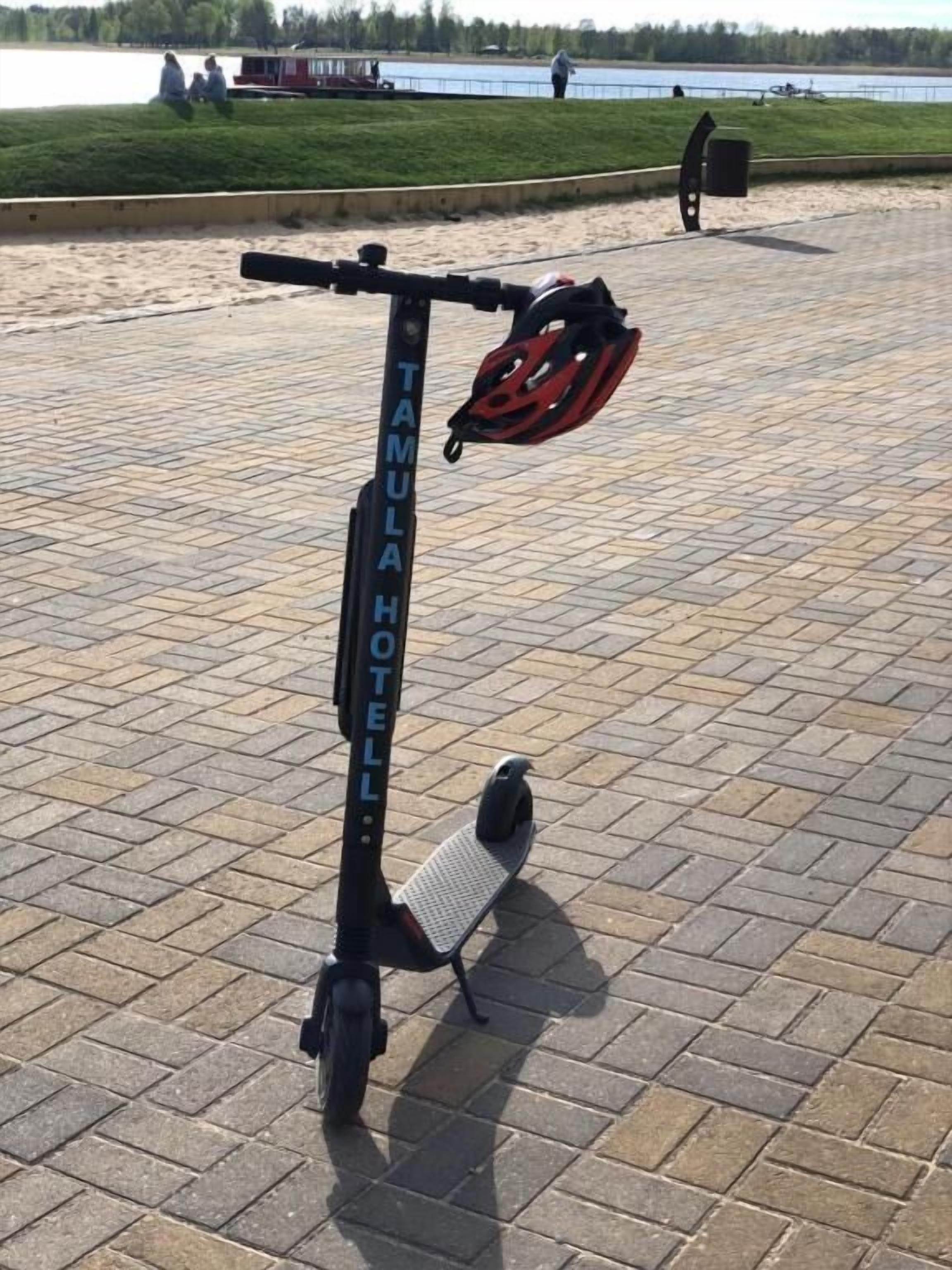 A stationary electric scooter with a helmet on the ground.