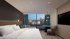 Una habitación de hotel moderna con una cama grande, un área de descanso con una mesa y un televisor en la pared.