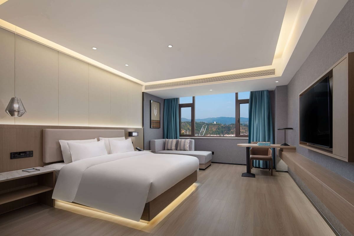 Une chambre d’hôtel moderne, dotée d’un grand lit, d’un bureau et d’une télévision.