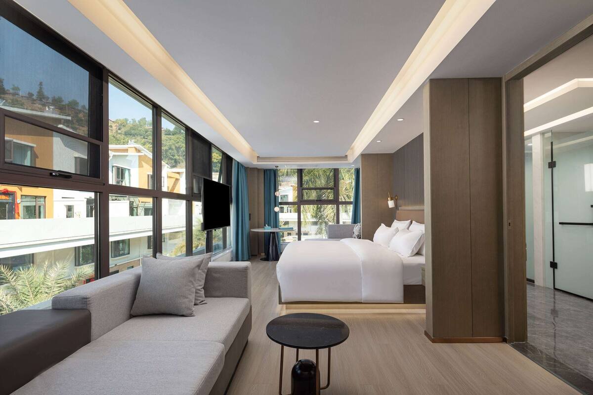 Une chambre d’hôtel moderne avec un grand lit, un canapé, une petite table et un téléviseur.