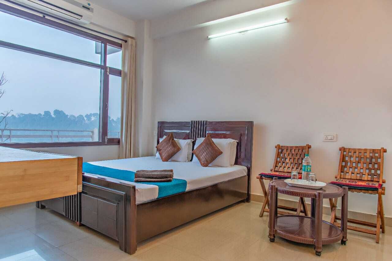 A hotel room with a bed, a desk, a chair, and a small table.