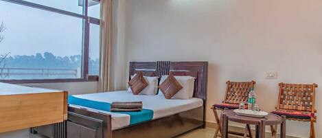 A hotel room with a bed, a desk, a chair, and a small table.