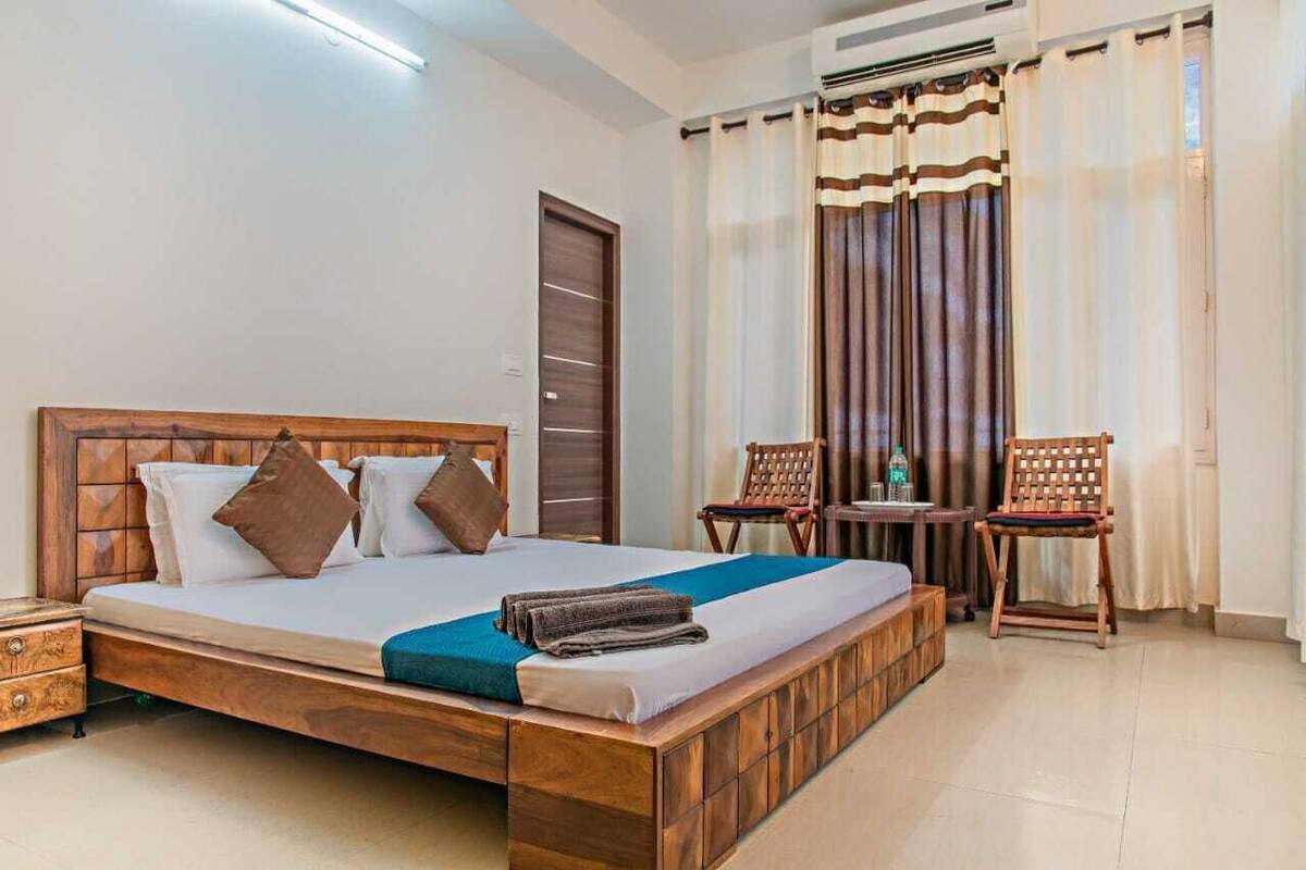 A bedroom with a wooden bed, a bedside table, a chair, and a small table with a bottle.