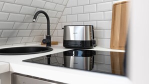 Une cuisine au design moderne, dotée d’une plaque de cuisson à induction noire et argentée, d’un robinet noir et d’une planche à découper en bois.