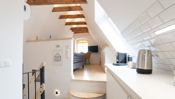 Une cuisine moderne avec un escalier en bois, un coin repas et un plan de travail équipé d’une bouilloire.
