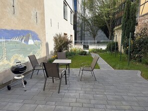 An outdoor patio with a table and chairs, a grill, and a mural on the wall. - Cozy attic apartment in the old town WLAN 100Mbit (Stralsund)