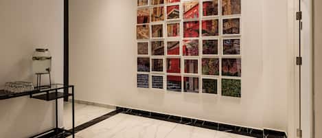 Ein modernes Interieur mit Fliesenboden, einer Wanddekoration aus Fotografien und einer minimalistischen Glasvitrine.