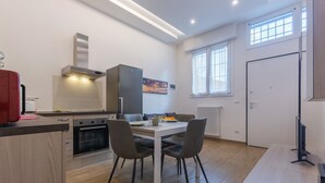 Eine moderne Küche mit Esstisch, Stühlen und einem Kühlschrank.