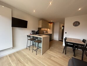Cozinha moderna com ilha central, banquetas e mesa de jantar com cadeiras.