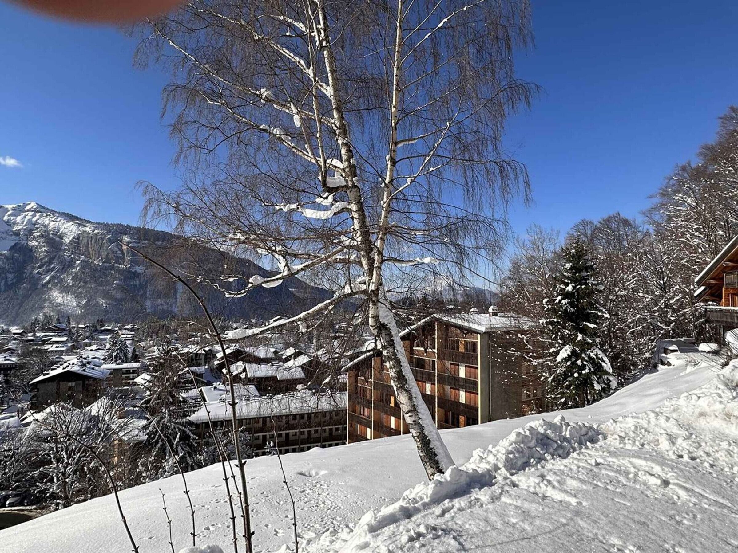 A snow-covered mountain landscape with a building featuring a grid-like facade and a sloped roof.