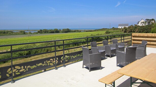 A terrace with wicker furniture and a wooden table, overlooking a green field and the sea. - Large house with pond and sea view, near the Lighthouse, garden and terraces, parking (Gatteville-le-Phare)