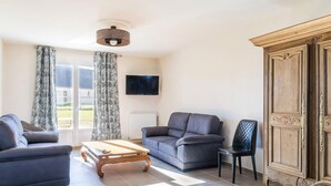 A living room with a sofa, a coffee table, a TV, and a cabinet. - Large house with pond and sea view, near the Lighthouse, garden and terraces, parking (Gatteville-le-Phare)