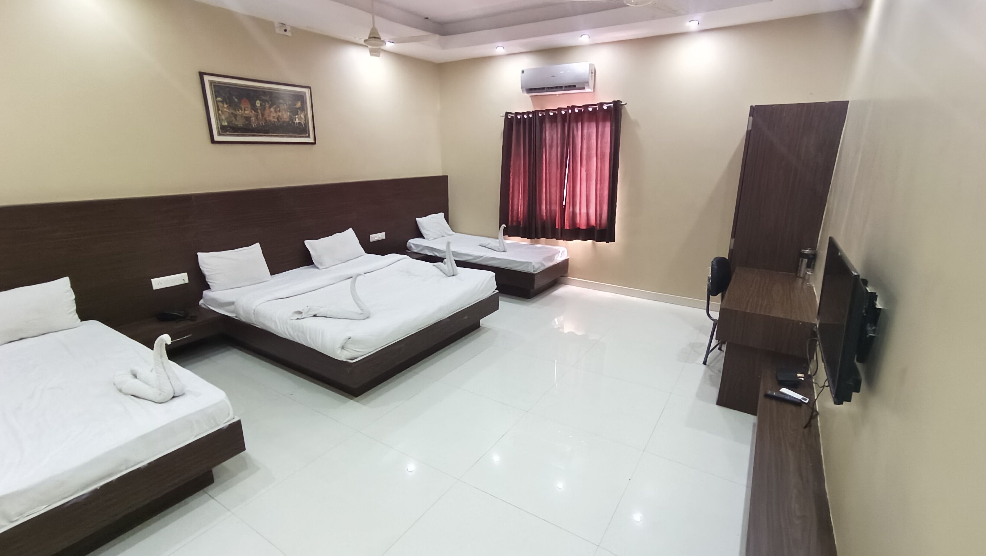 A hotel room with three beds, a flat-screen TV, an air conditioning unit, and a painting on the wall.