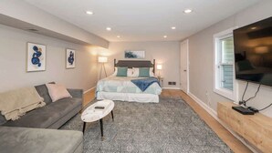 Un dormitorio moderno con cama, sofá, mesa de centro y televisor.