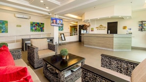 A hotel lobby with a reception desk, seating area, and a television screen. - Microtel by Wyndham South Forbes Near Nuvali (Biñan City)